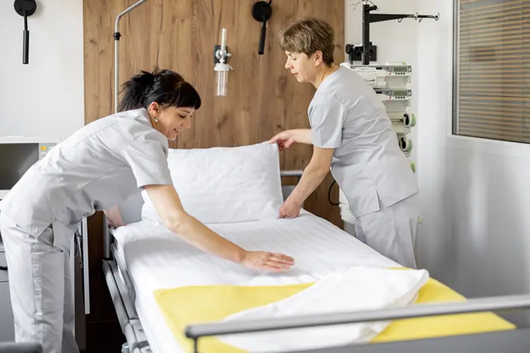 photo showing 2 cleaners making up a clean bed